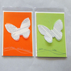 Bild: 2 Karten in orange und grü, mit weißem Schmetterling.