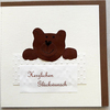 Bild: Karte mit Aufschrift „herzlichen Glückwunsch“ und dunkelbraunem Bär.